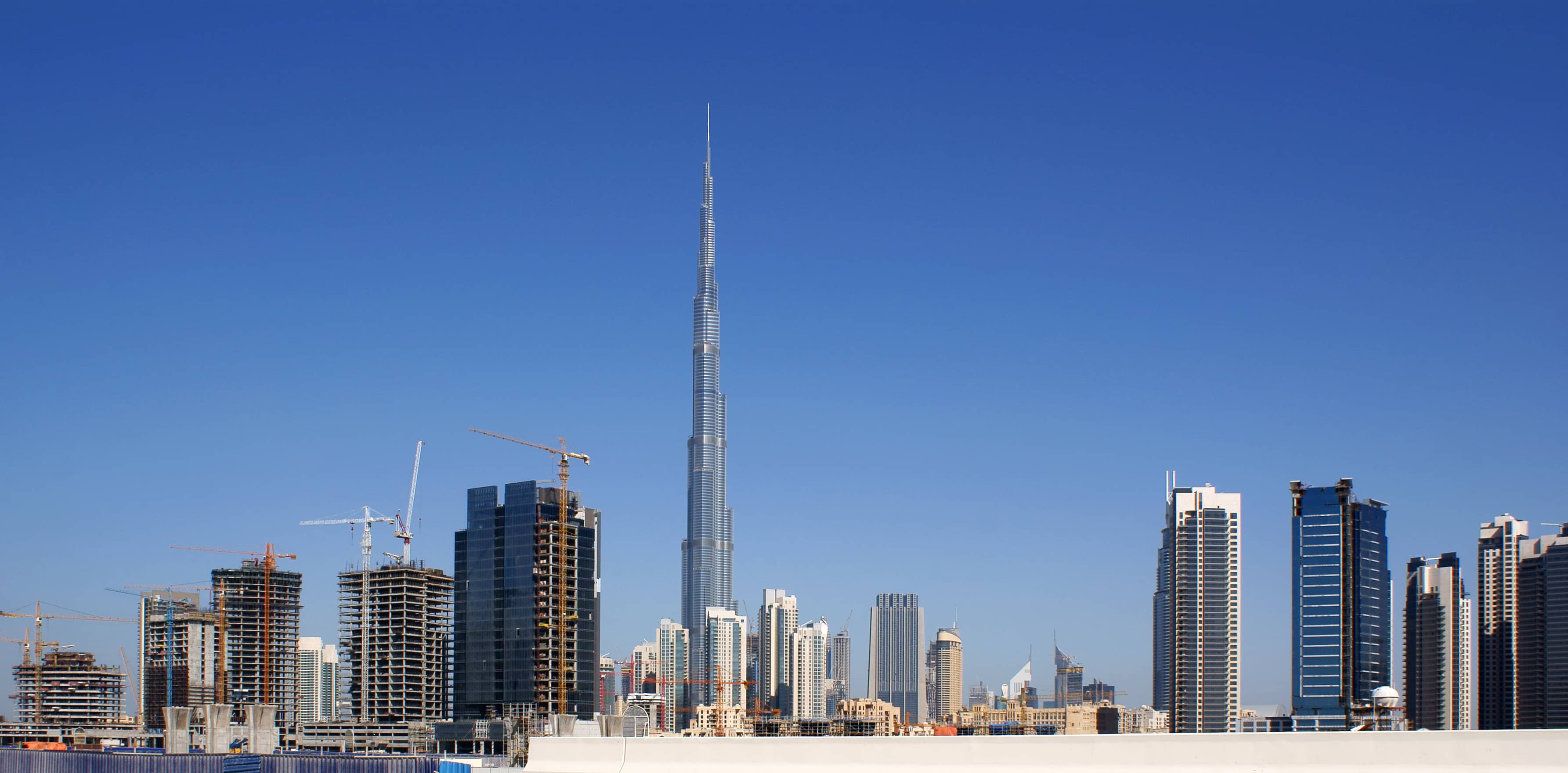 The Burj Khalifa rising above Dubai's skyline under a clear blue sky suitable=true index=0