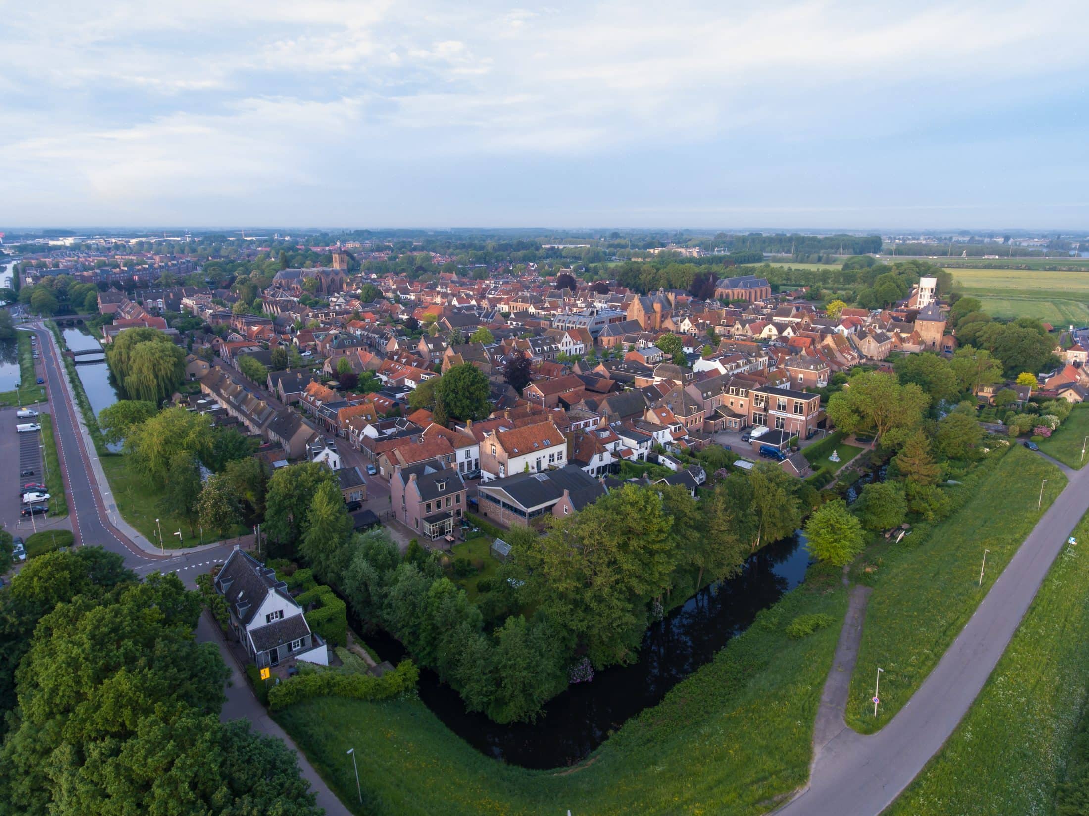 A cityscape of Vianen covered in buildings and greenery under a cloudy sky at daytime in the Netherlands